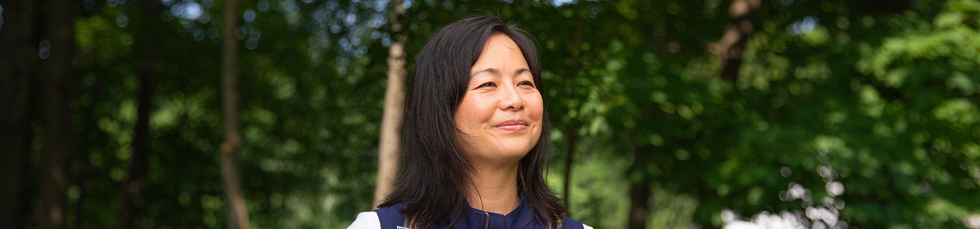  adult woman volunteer in vest outside hiking and smiling 